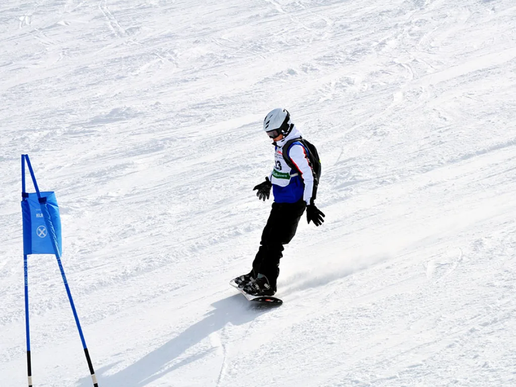 Snowboarderin fährt auf das blaue Tor zu.